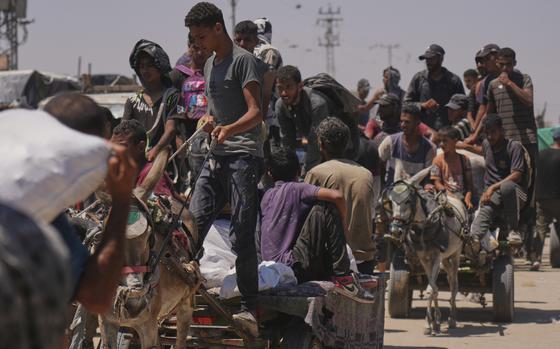 A line of people, some carrying or hauling aid packages.