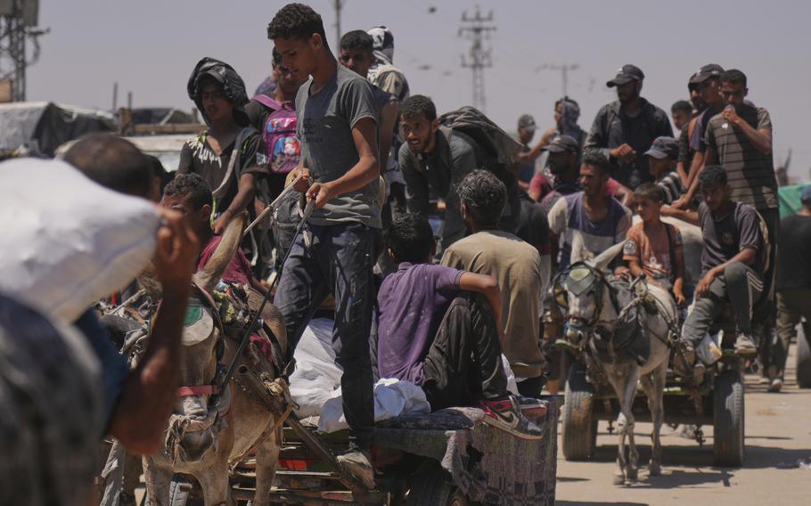 A line of people, some carrying or hauling aid packages.