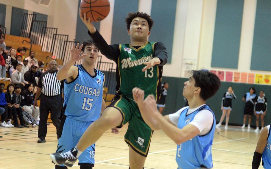 Daegu's Andrew Burks goes up for a shot between Osan's Benjamin Ziegler and M.J. Siebert during Saturday's Korea boys basketball game. The Warriors won 68-61.