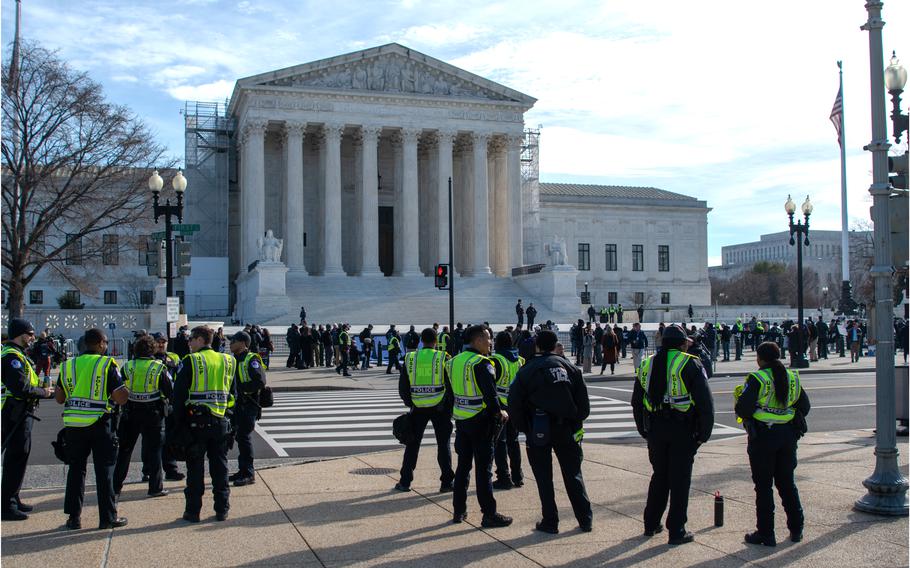 Security personnel stand at the ready across the street from the Supreme Court as demonstrators gather on Feb. 8, 2024.