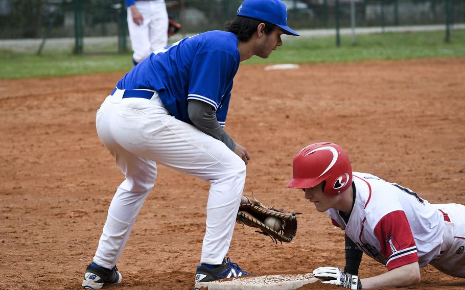 Kaiserslautern's Aidan Malcolm looks at the ball after barely getting back to first base during a pickoff attempt and swipe by Ramstein’s C.J. Delp during a game on Saturday, April 30, 2022, in Kaiserslautern, Germany.