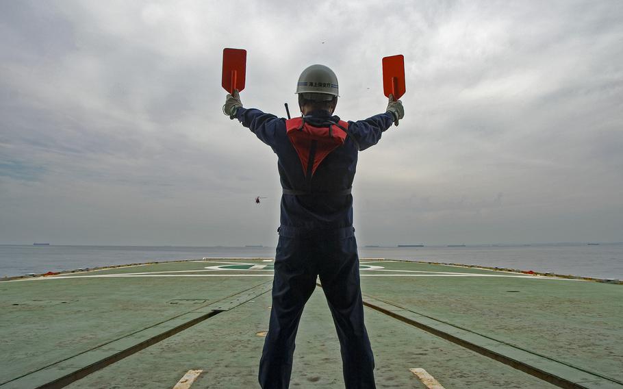 A flight crew onboard the Japanese Coast Guard Cutter Mizuho, prepares to land an HH-65 helicopter, on the Mizuho on Oct. 16, 2007, in Nagoya, Japan.