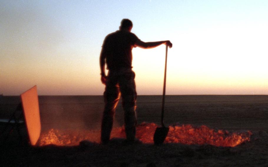 An American service member in the Saudi Arabian desert in 1991 tends a burning trash pit.