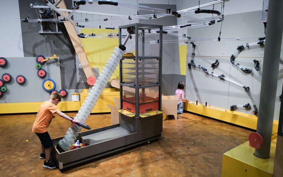 Two kids play in the wind tube station, exploring how air pressure can transport items in a vacuum at the Experimenta Science Center.