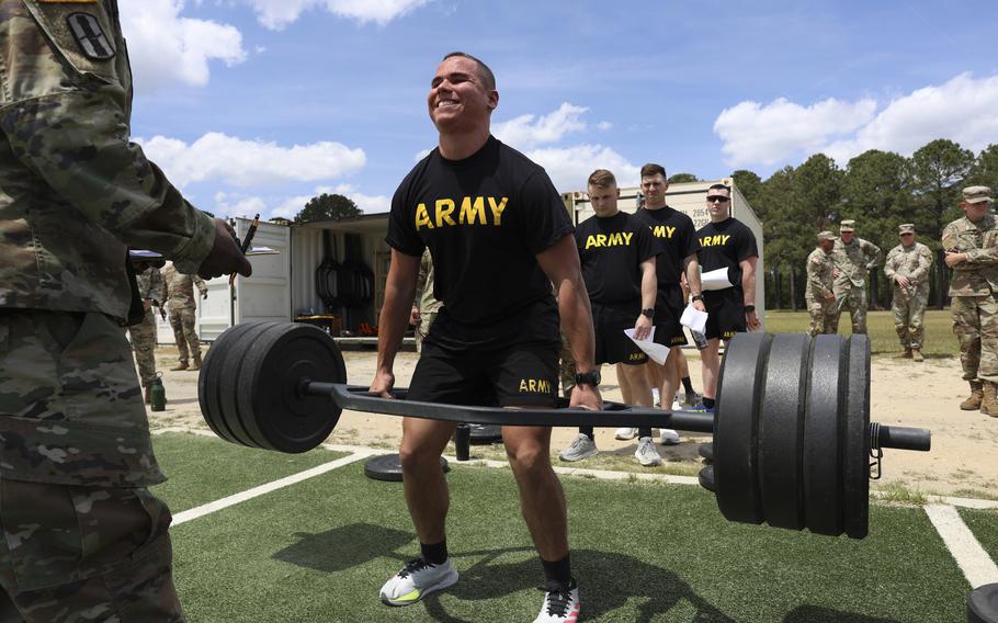 A soldier strains to lift a bar with heavy free weights.