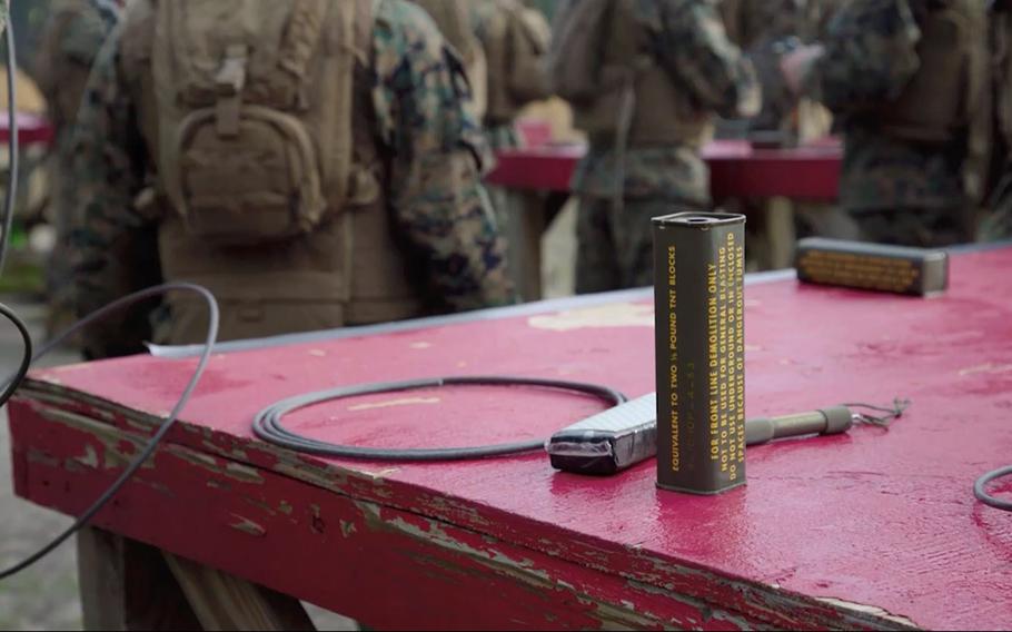 A photo shows a block of TNT as Marines train in the background at Camp Lejeune in Jacksonville, N.C.