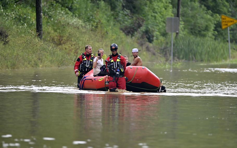 Members of the Winchester, Ky., Fire Department walk inflatable boats across flood waters over Ky. State Road 15 in Jackson, Ky., to pick up people stranded by the floodwaters Thursday, July 28, 2022. Flash flooding and mudslides were reported across the mountainous region of eastern Kentucky, where thunderstorms have dumped several inches of rain over the past few days.