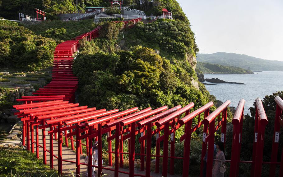 Stroll on a path beneath 123 torii gates toward picturesque sea views during a visit to Motonosumi Inari Shrine in Yamaguchi prefecture, Japan.