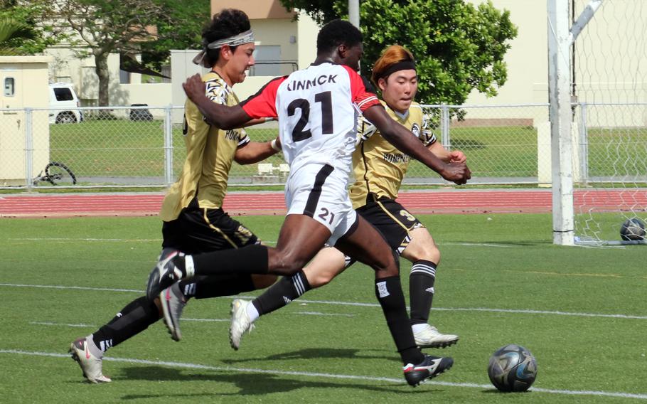Kinnick's Koboyo Awesso tries to dash around Humphreys' Craig An and Matthew Hwang.