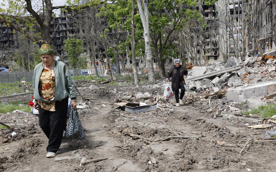 Women walk past a destroyed apartment building in Mariupol, in territory under the government of the Donetsk People’s Republic, eastern Ukraine, Monday, May 2, 2022.