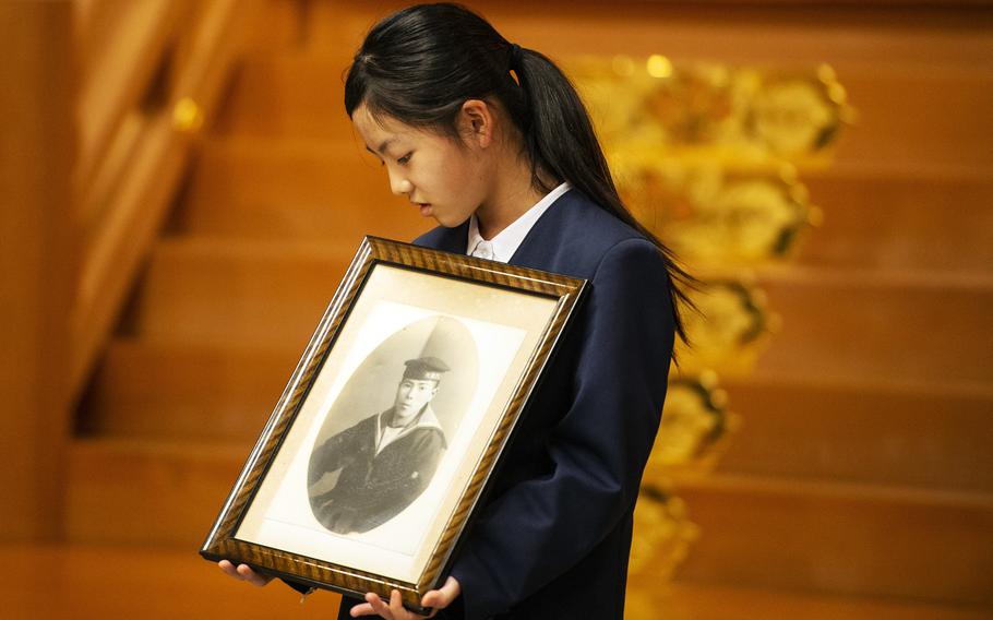 Akari Terahara, 11, holds a photo of her relative, Norito Myochin, during a flag-return ceremony at Gokoku Shrine in Hiroshima, Japan, Sunday, Dec. 4, 2022. 