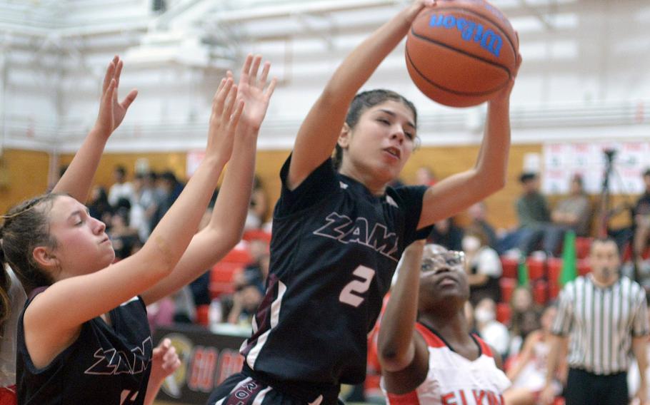 Zama's Isabella Rivera Munoz comes down with a rebound against E.J. King during Friday's DODEA-Japan girls basketball season-opening game. The Cobras won 69-33.