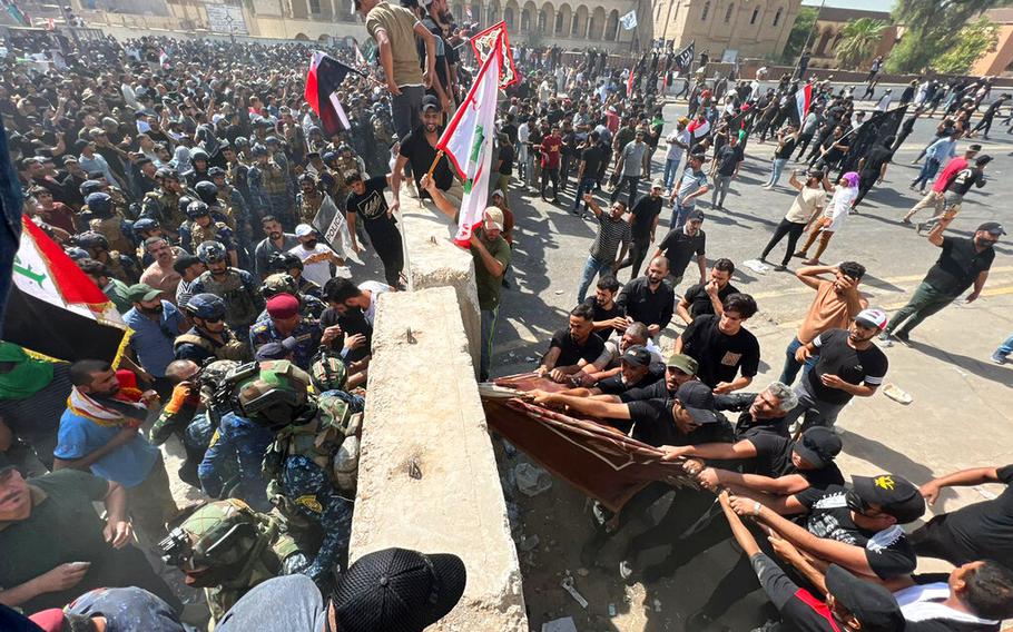 Protesters try to remove concrete barriers and cross the bridge towards the Green Zone area in Baghdad, Iraq, Saturday, July 30, 2022 — days after hundreds breached Baghdad’s parliament Wednesday chanting anti-Iran curses in a demonstration against a nominee for prime minister by Iran-backed parties.