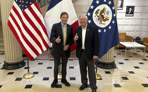 Blumenthal and Graham smile and give the thumb’s up, in front the U.S., France and U.S. presidential flags.