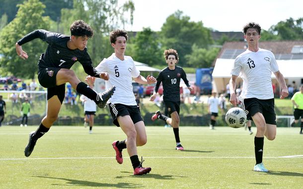 Bahrain forward Cesar Lopz shoots as Vicenza defenders, from left, Jacob McGovern and Colin Frazee chase him down during pool-play action of the DODEA Division II European championships on May 20, 2024, at VfB Reichenbach in Reichenbach-Steegen, Germany.