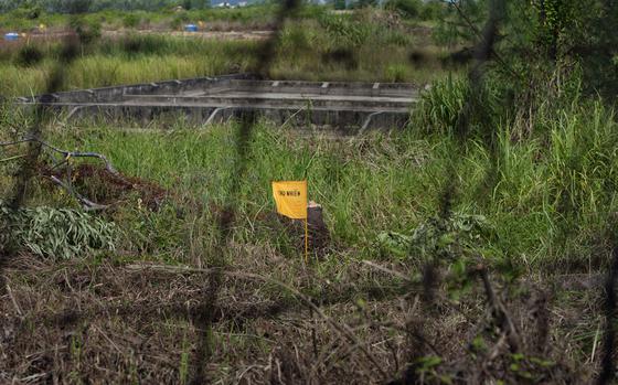 FILE- A yellow flag marks a field contaminated with dioxin near Danang airport, during a ceremony marking the start of a project to clean up dioxin left over from the Vietnam War, at a former U.S. military base in Danang, Vietnam Thursday Aug. 9, 2012. (AP Photo/Maika Elan, File)