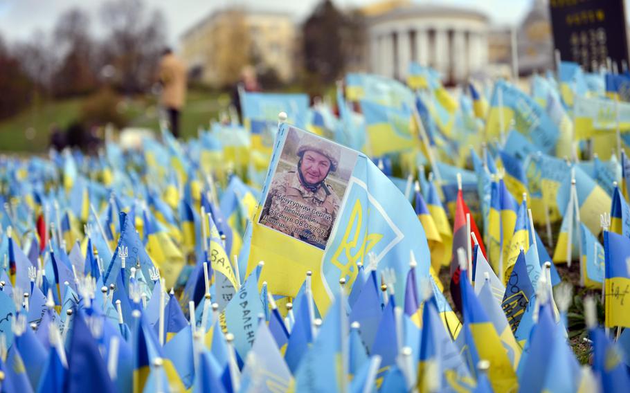 A photo of a Ukrainian soldier killed in May rests among hundreds of small flags commemorating war dead at the Maidan Nezalezhnosti, the central square of Kyiv, the country’s capital, on Oct. 26, 2022.