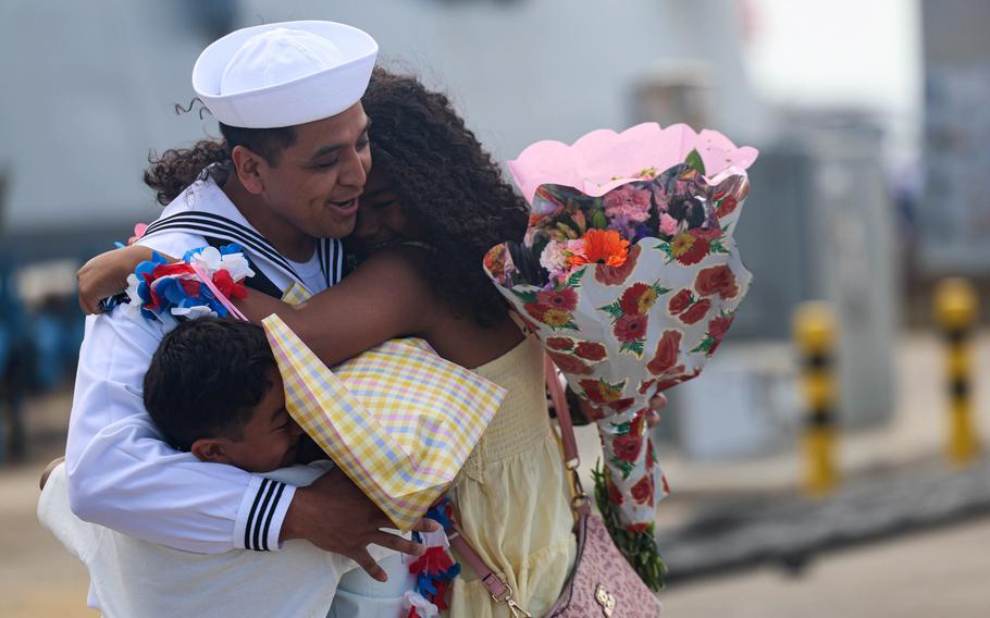 A sailor embraces a woman and child.