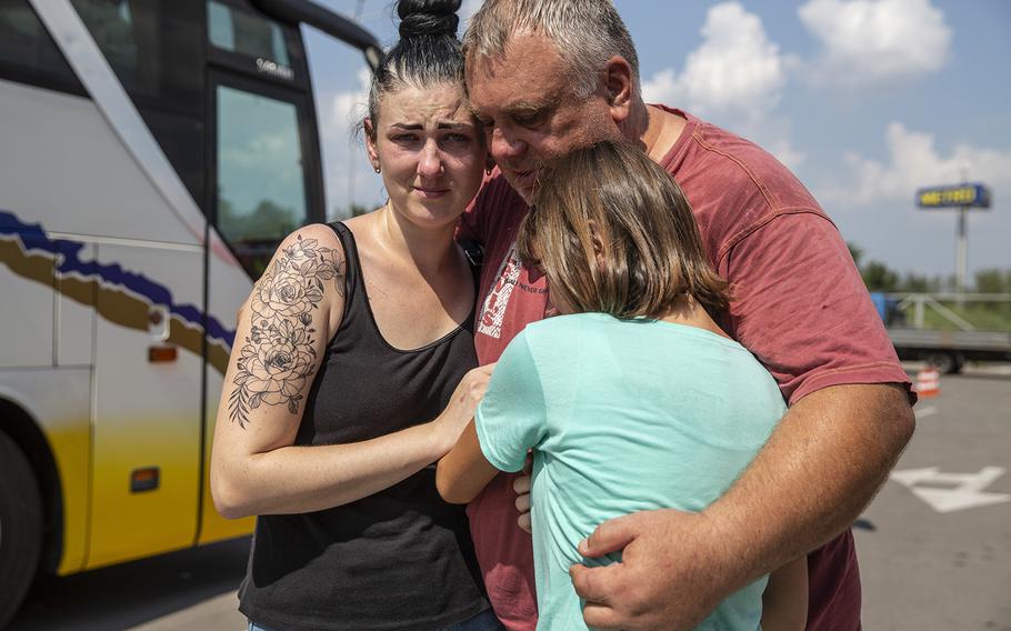 Serhil Ardolyanova, 54, embraces his daughters, Inna, 31, and Masha, 10, before they depart on an evacuation bus at a humanitarian aid center for internally displaced people in Zaporizhzhia, Ukraine, on Aug. 19, 2022.