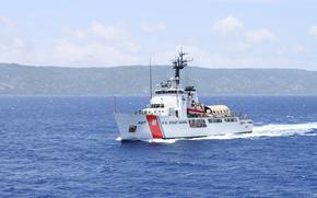 A Coast Guard cutter in water, with land visible in the background.