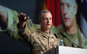 Gen. Alexus Grynkewich gestures behind a podium as he speaks in uniform.