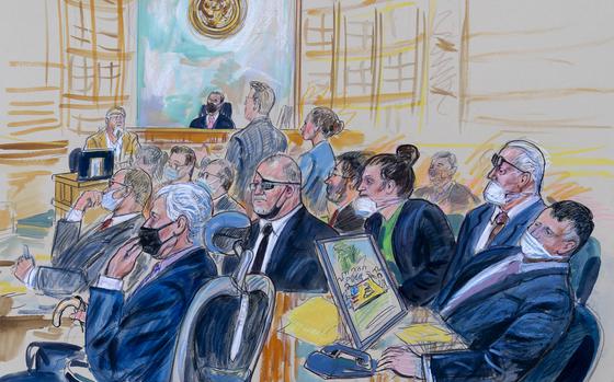 FILE - This artist sketch depicts the trial of Oath Keepers leader Stewart Rhodes and four others charged with seditious conspiracy in the Jan. 6, 2021, Capitol attack, in Washington, Oct. 6, 2022. Shown above are, witness John Zimmerman, who was part of the Oath Keepers' North Carolina Chapter, seated in the witness stand, defendant Thomas Caldwell, of Berryville, Va., seated front row left, Oath Keepers leader Stewart Rhodes, seated second left with an eye patch, defendant Jessica Watkins, of Woodstock, Ohio, seated third from right, Kelly Meggs, of Dunnellon, Fla., seated second from right, and defendant Kenneth Harrelson, of Titusville, Fla., seated at right. Assistant U.S. Attorney Kathryn Rakoczy is shown in blue standing at right before U.S. District Judge Amit Mehta. U.S. Army veterans Watkins and Harrelson are scheduled to be sentenced on Friday, May 26, 2023 (Dana Verkouteren via AP)