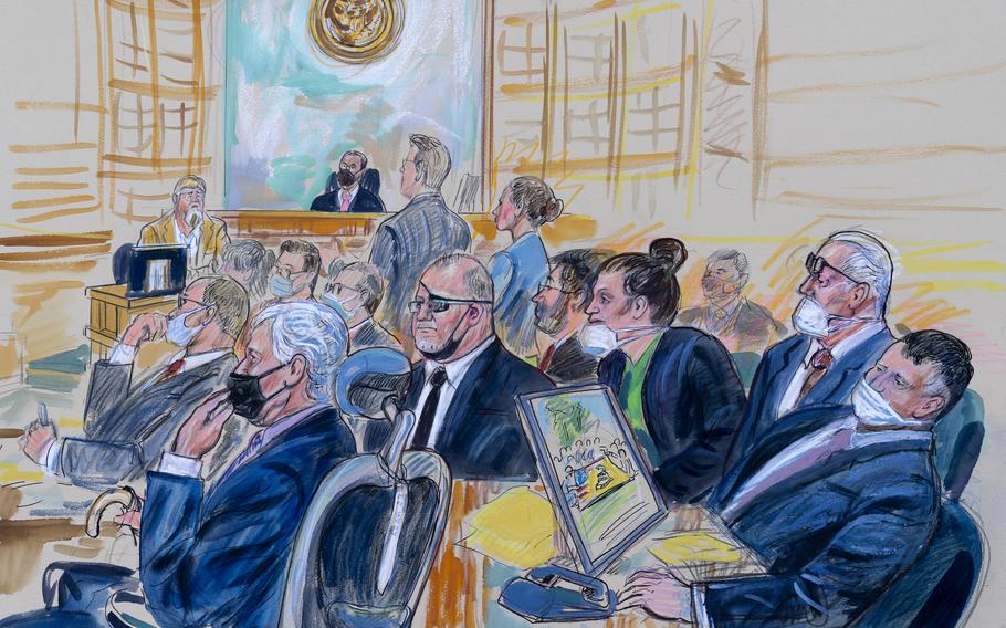 This artist sketch depicts the trial of Oath Keepers leader Stewart Rhodes and four others charged with seditious conspiracy in the Jan. 6, 2021, Capitol attack, in Washington, Oct. 6, 2022. Shown above are, witness John Zimmerman, who was part of the Oath Keepers’ North Carolina Chapter, seated in the witness stand, defendant Thomas Caldwell, of Berryville, Va., seated front row left, Oath Keepers leader Stewart Rhodes, seated second left with an eye patch, defendant Jessica Watkins, of Woodstock, Ohio, seated third from right, Kelly Meggs, of Dunnellon, Fla., seated second from right, and defendant Kenneth Harrelson, of Titusville, Fla., seated at right. Assistant U.S. Attorney Kathryn Rakoczy is shown in blue standing at right before U.S. District Judge Amit Mehta. U.S. Army veterans Watkins and Harrelson are scheduled to be sentenced on Friday, May 26, 2023.