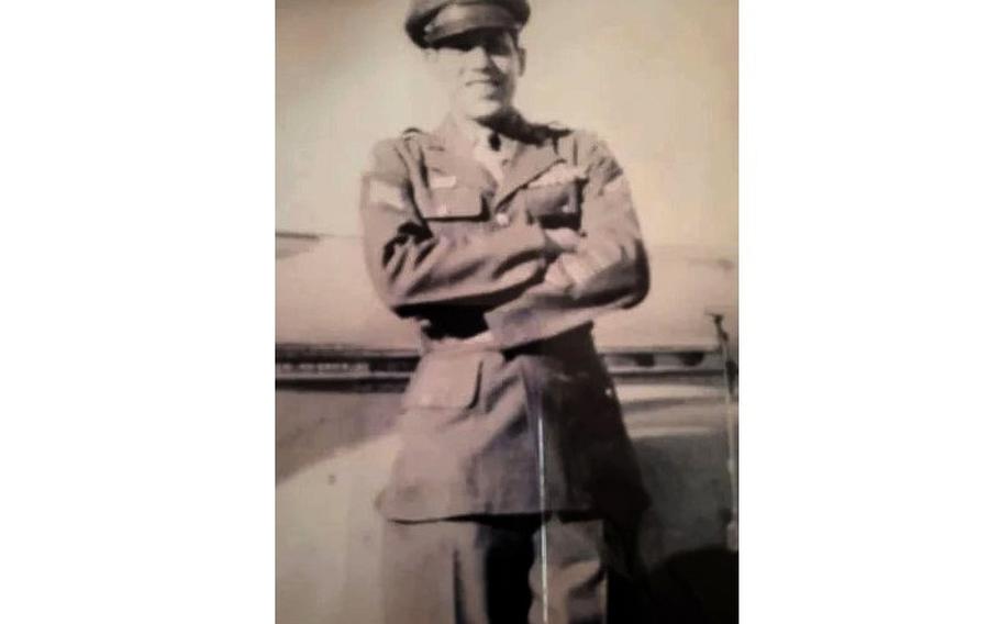 A black-and-white, 1940s-era photo of a military service member posing with his arms crossed in front of him while wearing dress uniform and hat.