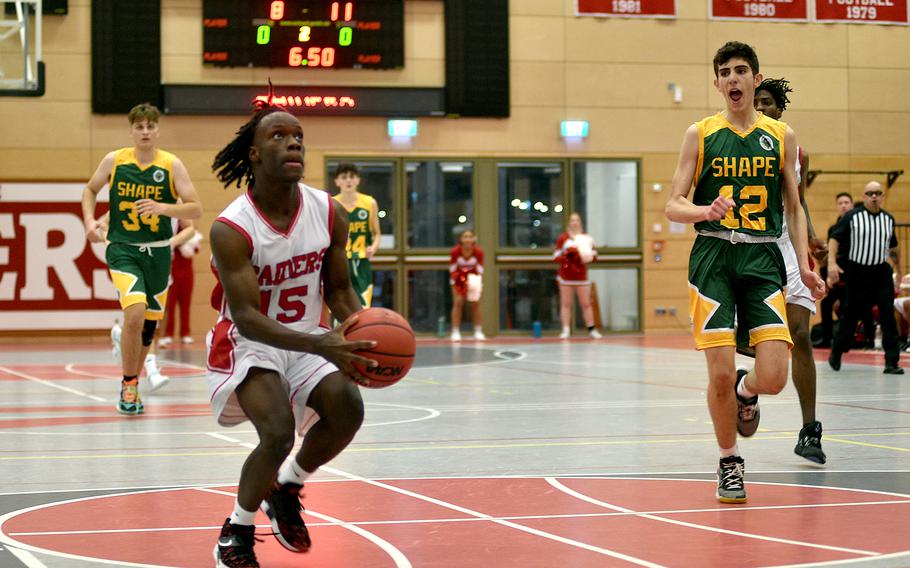 Kaiserslautern's Davis Martin heads up for a layup as SHAPE's Irakitas Manosakis tries to get back on defense during Friday evening's game at Kaiserslautern High School in Kaiserslautern, Germany. Trailing the play, left, is the Spartans' Thomas Tsoulas.