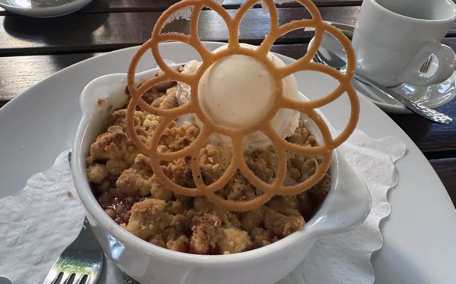 A dessert of  strawberry-rhubarb crumble served with a scoop of vanilla ice cream.