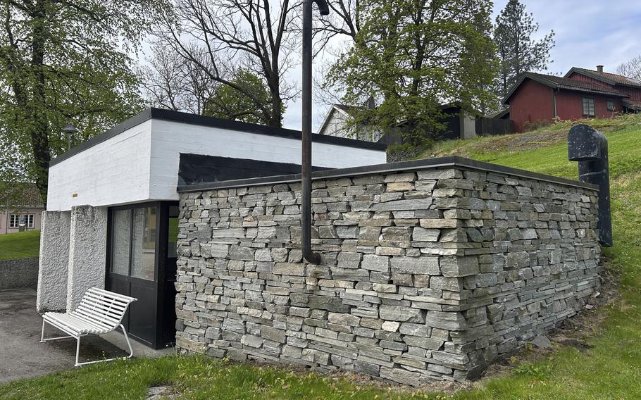 A small stone building nestled in a hill, below houses.
