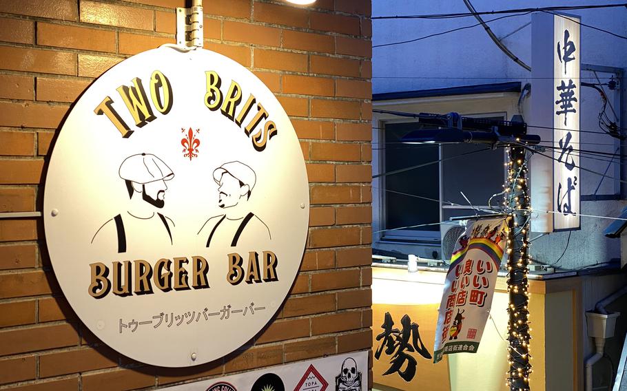 A round sign on a brick wall says Two Brits Burger Bar.