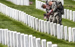 Service members place flags on graves at Arlington National Cemetery before Memorial Day in 2012.