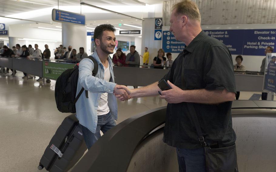 Michael White, a Navy veteran who was jailed in Iran for several years on spying charges, right, shakes hands with Michael's former fellow prisoner and Iranian political activist Mahdi Vatankhah at the Los Angeles International Airport in Los Angeles, Thursday, June 1, 2023. 