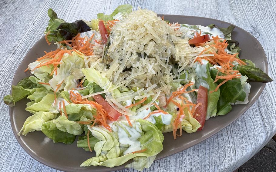 Spinach dumplings topped with cheese and onions, served with salad..