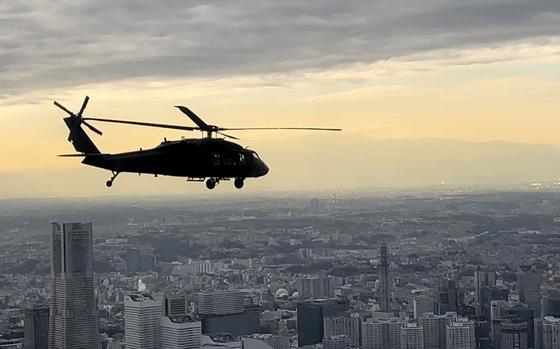 A U.S. Army UH-60L Black Hawk flies over Tokyo Bay with the Yokohama Landmark Tower in the background, Tuesday, Jan. 17, 2023.