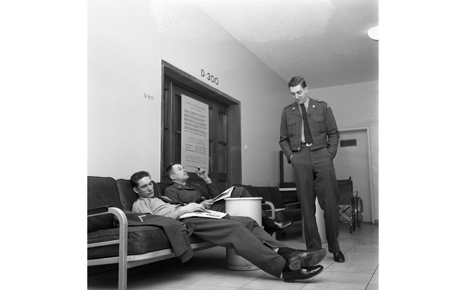 Soldiers sleep, pace and smoke in the waiting room of the 97th General Hospital Maternity Ward in Frankfurt, Germany, awaiting the news that mother and child are OK. 