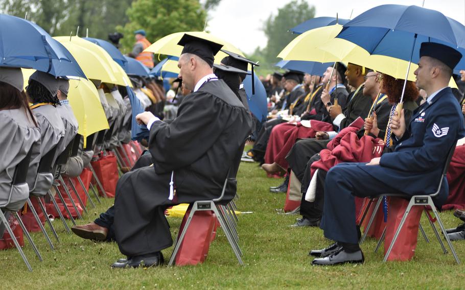 Graduates sit under umbrellas during a brief rain shower during commencement for the University of Maryland Global Campus Europe class of 2022 on Saturday, April 30, 2022, in Obersuelzen, Germany.