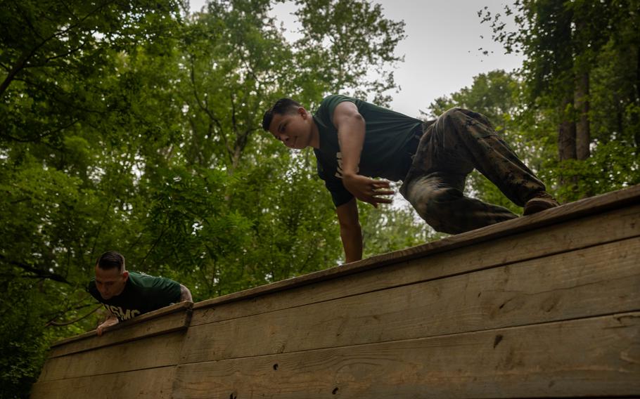 Marines climb over a wooden wall.