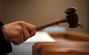 A hand wields a gavel.