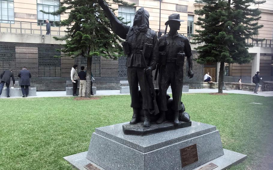 A metal statue of two people stands in a grassy park.