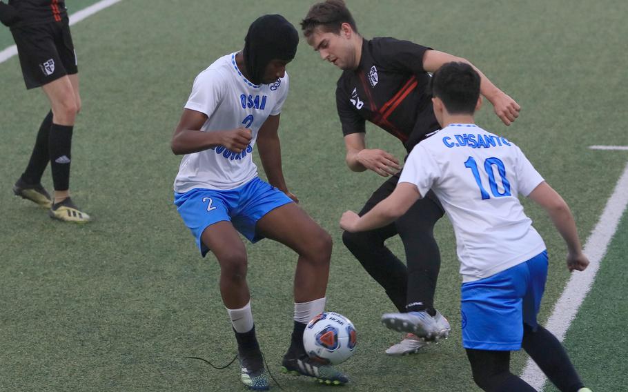 Seoul Foreign's George Rooker Roberts gets hemmed in by Osan's Justiss Parker-Jones and Cannon DiSanto during Wednesday's Korea boys socceer match. The Crusaders won 10-0.