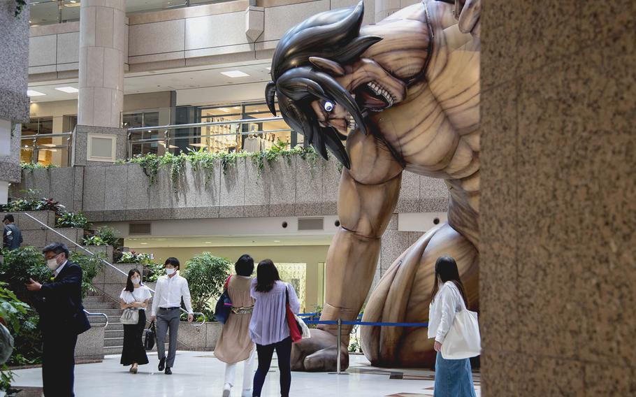 Visitors to Yokohama Landmark Tower wear masks while passing the "Attack on Titan" exhibit in Yokohama, Japan, May 24, 2021.  