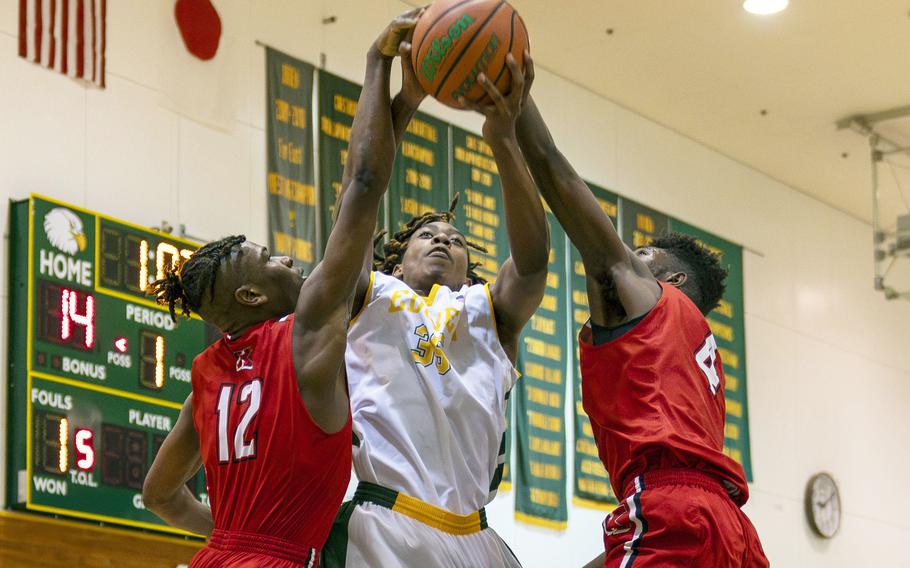 Nile C. Kinnick's Nicholas Whyte and Kennedy Hamilton and Robert D. Edgren's JaShawn Spaights-Pace go up for the ball during Friday's DODEA-Japan boys basketball game. The Red Devils won 80-78.