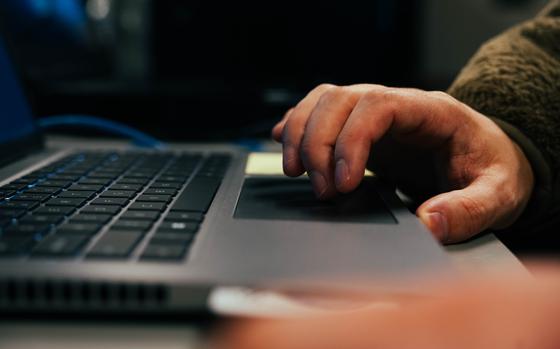 A closeup of hands using the track pad on a laptop.