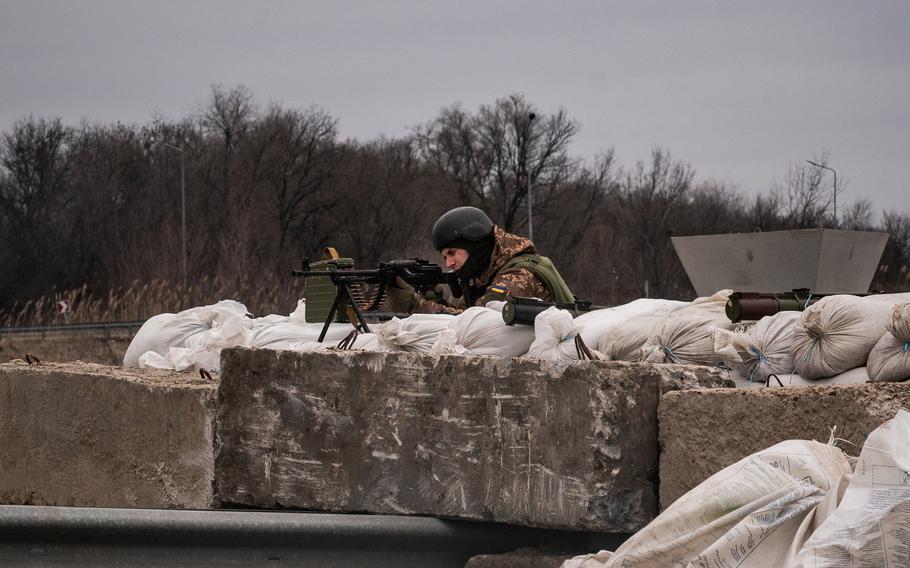 A Ukrainian soldier gets into position as vehicles approach a checkpoint near the city of Dnipro. 