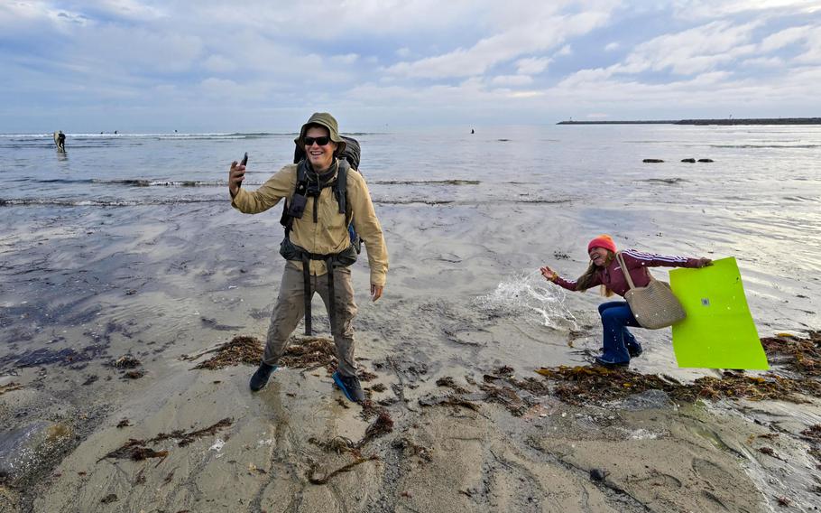 U.S. Army veteran Alex Seling is all smiles as his friend, Cecylia Mares, splashes him with water from the Pacific Ocean after he ended his coast-to-coast walk at Doheny State Beach in Dana Point, Calif., on Monday, January 31, 2022. Seling left Cape Henlopen State Park in Delaware on Dec. 21, 2020, hiking more than 4,000 miles to raise awareness and funds to prevent veteran suicide.