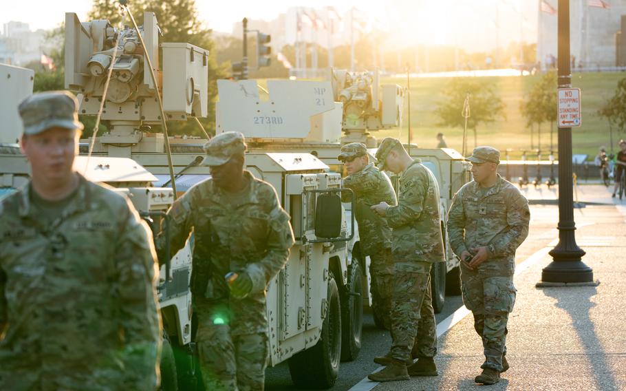 Soldiers stand by their military vehicles.