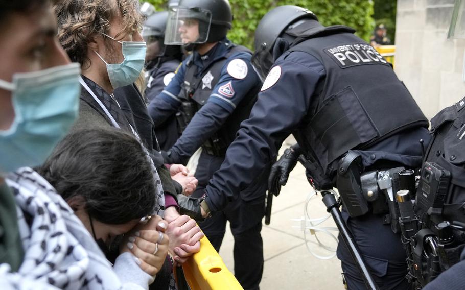 A pro-Palestinian protester rests her head on her clasped hands while she stands before University of Chicago police officers while officers keep protesters from the university’s quad while the student encampment is dismantled, Tuesday, May 7, 2024, in Chicago.
