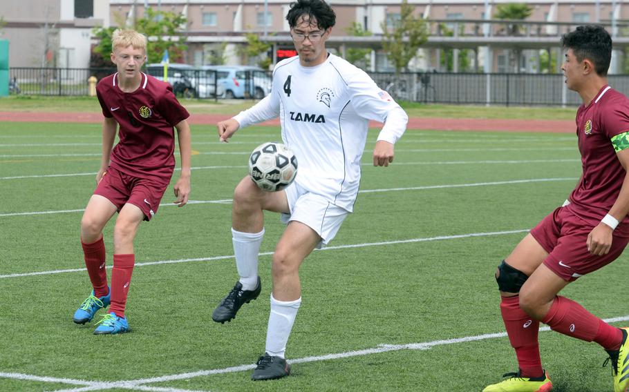 Zama’s Greg Horton plays the ball between Matthew C. Perry’s Samuel Williams and Ren Spinosi during Saturday’s DODEA-Japan boys soccer match. The teams played to a 1-1 draw.